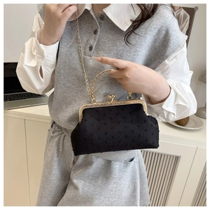 Detail of retro black polka dot fabric handbag featuring gold metal clasp and ring handle