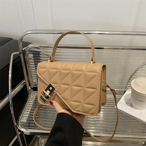 Chic khaki quilted crossbody bag with gold hardware on a modern minimalist chair