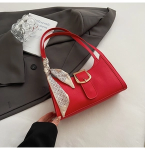 Detail of red croc-effect baguette bag with silk scarf on a stylish minimalist background