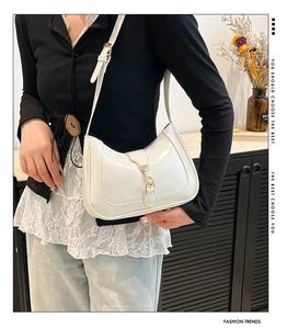 Detail of white patent leather shoulder bag with a gold buckle and adjustable strap