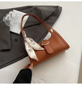 Detail of crocodile texture leather baguette bag with silk scarf and vintage gold buckle