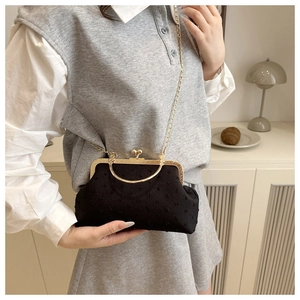 Dettaglio borsa vintage nera con texture a pois 3D e manico elegante in metallo oro