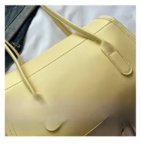 Detail of precise stitching and premium matte leather texture on the cream tote bag