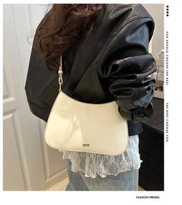 Sac sous le bras demi-lune blanc crème à la mode avec logo en métal sur l'épaule d'un mannequin