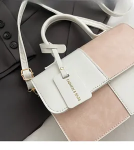 Detail of pink and white contrast handbag with gold hardware on a grey blazer