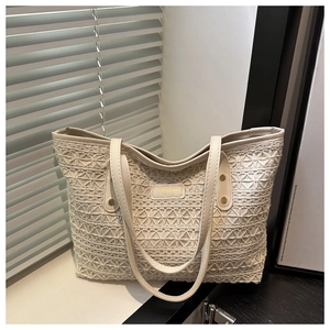 Close-up of geometric hollow lace texture and leather brand label on a cream tote bag