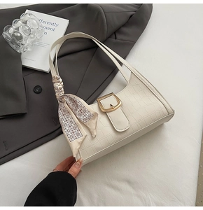Close-up of white crocodile pattern shoulder bag with golden buckle and silk scarf