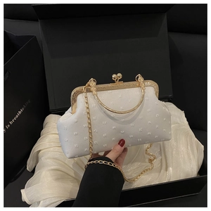 Dettaglio di borsa da sera vintage bianca con cornice in metallo dorato e chiusura a scatto
