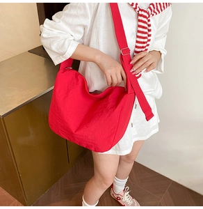 Detail view of large red nylon crescent bag with adjustable wide shoulder strap on model
