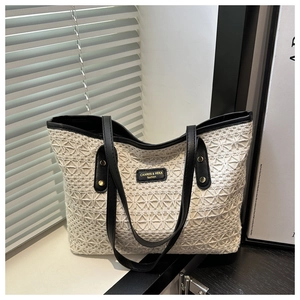 Detail of the woven hollow-out pattern and leather strap on the ivory tote bag