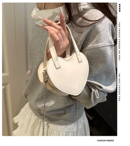 Détail du mini sac coeur crème avec bandoulière chaîne et lettrage embossé discret