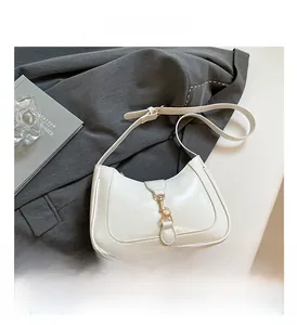 Detail of a creamy white saddle bag with golden metal buckle and moon-shaped design