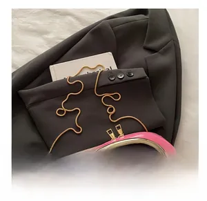 Detail of bright pink clutch with a large gold metal handle and elegant chain strap