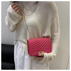 Détail d'un sac bandoulière rose fuchsia avec matelassage en V et chaîne dorée