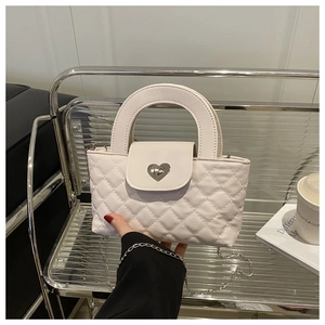 Detail einer weißen Stepptasche mit silbernem Herz-Drehverschluss und feiner Kette
