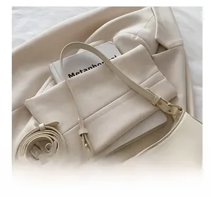 Détail du sac à main minimaliste crème avec finitions dorées et bandoulière réglable