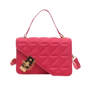 Magenta quilted crossbody bag with gold metal lock and elegant top handle on white background