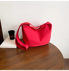 Close-up of vibrant red hobo bag on a wooden table with soft interior lighting