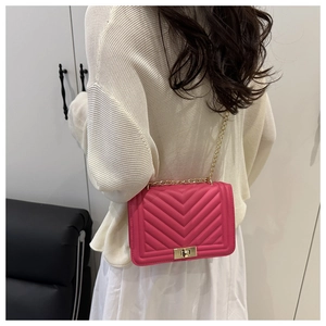 Magenta crossbody bag with V-shaped quilting and gold chain strap shown on model