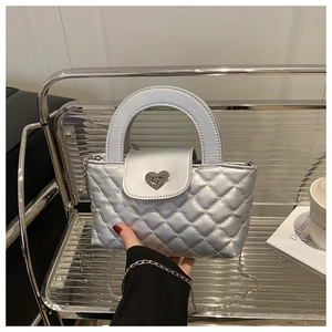 Detail einer silbernen Stepptasche mit Herz-Metallschloss und elegantem Kettenriemen