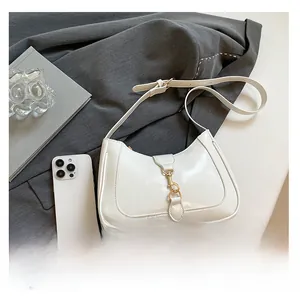 Detailed comparison of white hobo bag size with a smartphone on a grey blazer background