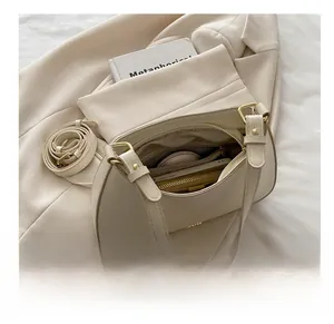 Sac bandoulière beige en demi-lune montrant l'espace de rangement intérieur