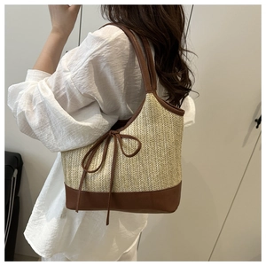 Close-up of a straw tote bag featuring a leather bow and fine woven texture details