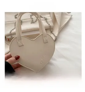 Gros plan d'un sac cœur en cuir PU crème avec gravure Jin pin et bandoulière chaîne