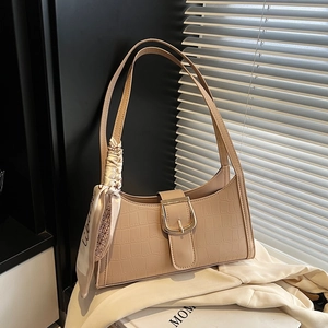 Chic beige crocodile texture baguette bag with silk scarf on neutral fabric background