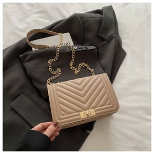 Detail of V-quilted khaki chain bag with a gold-tone twist lock on grey blazer