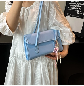 Detail of light blue glossy leather shoulder bag with cute pink charm and woven cord
