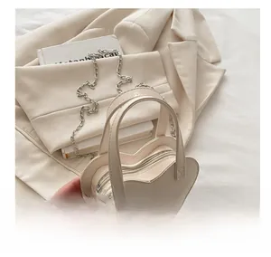 Détail du sac à main crème en forme de cœur avec bandoulière chaîne sur un blazer