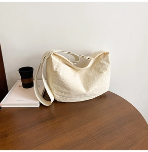 Detailed macro view of the cream-white hobo bag showing its unique wrinkled fabric texture
