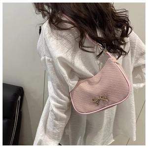 Detail of pink corduroy hobo bag with a gold bow accent worn over the shoulder