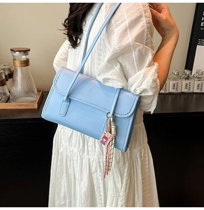 Close-up of a light blue underarm bag with cute cartoon charm and braided tassel detail
