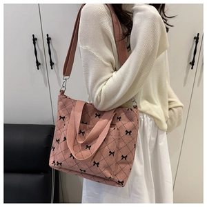 Dettaglio tote bag in velluto a coste rosa con motivi a fiocco nero e tracolla larga