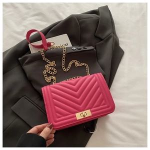 Close-up of fuchsia V-quilted texture with golden twist lock and metal chain strap