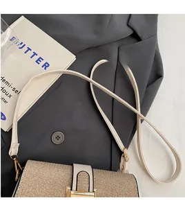 Close-up of champagne gold sequined square bag with slim leather strap on a grey blazer