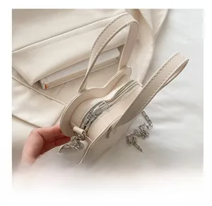 Gros plan détaillé du zip argenté et de la chaîne sur le sac beige en forme de cœur