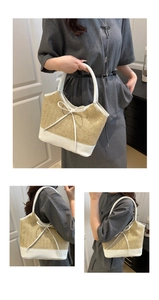 Detail of hand-woven straw tote bag featuring white faux leather handles and bow decoration