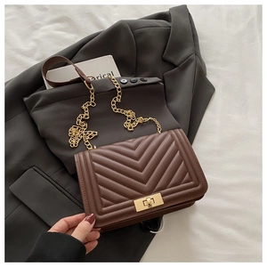 Detail of brown quilted crossbody bag with golden turn-lock and V-shaped stitching