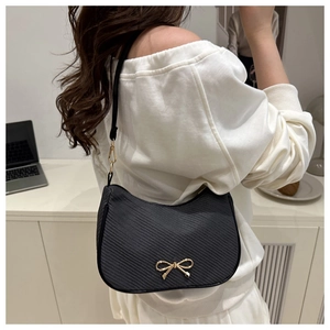Close-up of black crescent shoulder bag with golden bow hardware and twill texture