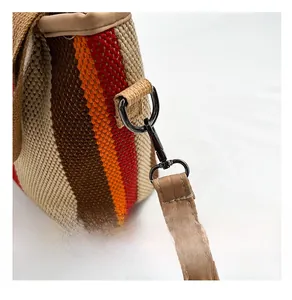 Macro detail of high-quality metal D-ring and lobster clasp on striped woven bag