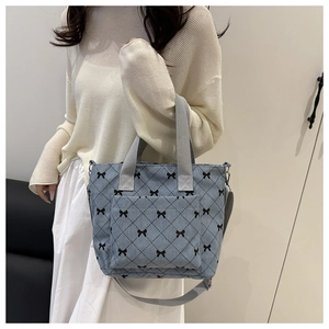 Dettaglio della borsa tote in velluto blu con fiocco e tracolla grigia indossata