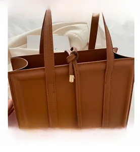 Detail view of brown square tote bag featuring elegant drawstring with gold hardware