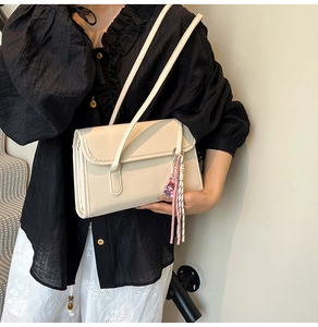 Cream shoulder bag detail featuring elegant fringe tassel and smooth leather texture