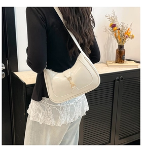 Chic cream white hobo bag with gold piston clasp worn by model in minimalist setting