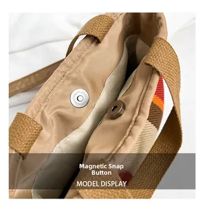 Detail view of the magnetic closure on a striped canvas tote bag with warm tones