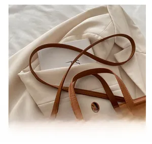 Detail of caramel faux leather shoulder straps with neat stitching and double-strap structure