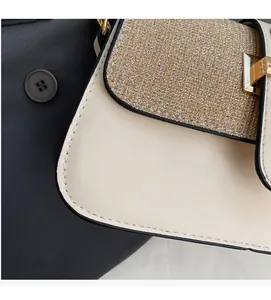 Close-up of beige leather crossbody bag featuring a gold metallic fabric flap and buckle